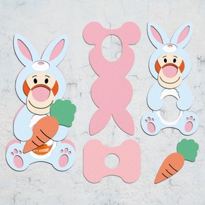 May include: A set of printable bunny and bear cutouts. The bunny is light blue with a carrot and the text "with surprise". The bear is pink and has a hole in the middle.