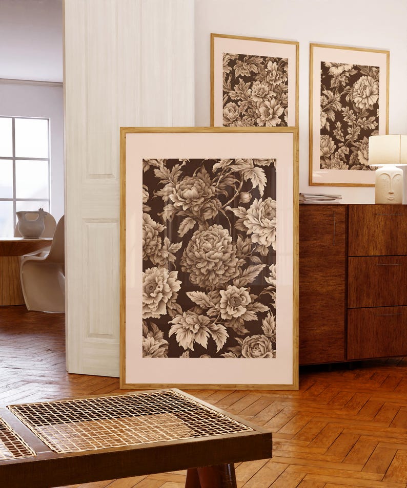 以下が含まれることがあります： 茶色の色合いの花柄が描かれた額装されたプリントが3枚。プリントは白い壁に木製のドレッサーの上に飾られています。
