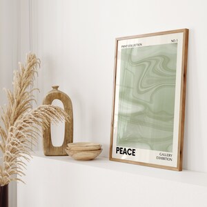 Pode incluir: Uma impress&atilde;o emoldurada com um design abstrato verde claro e a palavra "PEACE" em negrito. A impress&atilde;o faz parte de uma "PRINT COLLECTION" e "GALLERY EXHIBITION". Ta&ccedil;as de madeira e uma escultura de madeira entalhada tamb&eacute;m s&atilde;o vis&iacute;veis.