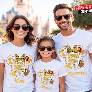 Könnte beinhalten: Weiße T-Shirts mit dem Thema König der Löwen. Jedes Shirt hat eine gelb-schwarze Schleife, die Worte "Hakuna Matata" und Zeichentrickfiguren. Die Shirts sind mit "Baby", "Mutter" und "Schwester" beschriftet.