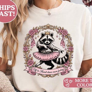 Könnte beinhalten: Cremefarbenes T-Shirt mit einem Waschbären in einem rosa Tutu und Krone, umgeben von einem floralen Kranz mit Ballettschuhen. Der Text "Off to Momit dance mom foolery" befindet sich auf einem Banner. Das Shirt hat auch den Text "MORE TEE COLORS!"