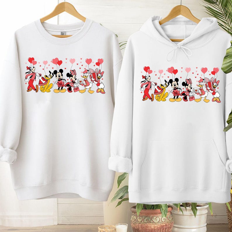 Pu&ograve; includere: Felpa e felpa con cappuccio bianche con una grafica dei personaggi Disney, tra cui Topolino e Minnie, Pippo, Paperino e Paperina, che tengono in mano palloncini a forma di cuore. Il design &egrave; rosso, nero e giallo.