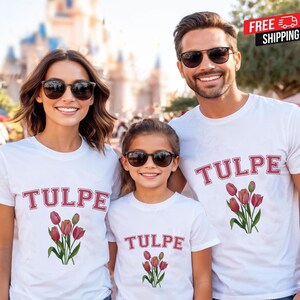 Puede incluir: Tres personas con camisetas blancas con la palabra "TULPE" en rojo, con contorno. Debajo, un gráfico de tulipanes rojos con tallos y hojas verdes. Los tres llevan gafas de sol.