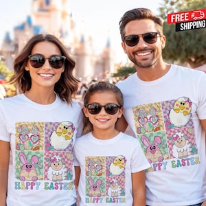 Könnte beinhalten: Drei Personen tragen weiße T-Shirts mit einem farbenfrohen Oster-Motiv. Das Motiv zeigt einen Hasen, ein Küken und ein Schaf mit dem Schriftzug "Happy Easter". Der Hintergrund ist eine verschwommene Szene im Freien.