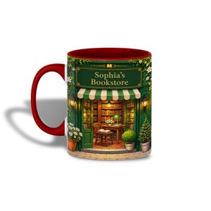 Könnte beinhalten: Ein Keramikbecher mit rotem Henkel und rotem Innenraum, bedruckt mit einer Illustration einer Buchhandlung mit grünem Vordach, Bücherregalen, einem Holzstuhl und Topfpflanzen. Der Text Sophia's Bookstore ist in Gold aufgedruckt.