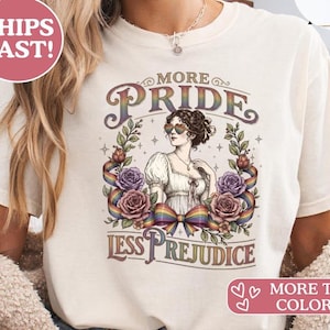 Könnte beinhalten: Cremefarbenes T-Shirt mit dem Aufdruck „More Pride, Less Prejudice“. Das Design zeigt eine Frau mit herzförmiger Sonnenbrille, umgeben von Rosen und einem Regenbogenband. Das T-Shirt hat kurze Ärmel.