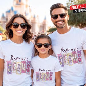 Könnte beinhalten: Drei weiße T-Shirts mit dem Text "Easter is for JESUS" in einem farbenfrohen Design. Die Shirts werden von einer dreiköpfigen Familie getragen, die alle eine Sonnenbrille tragen. Der Hintergrund ist verschwommen und deutet auf eine Umgebung im Freien hin.