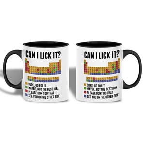 Könnte beinhalten: Zwei weiße Keramikbecher mit schwarzen Griffen und Rändern. Jeder Becher zeigt den Text "CAN I LICK IT?" über einem farbenfrohen Periodensystem-Design. Darunter befinden sich farbcodierte Aussagen.