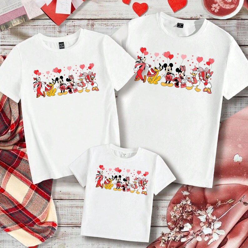 Pu&ograve; includere: T-shirt bianche con un design a cartoni animati di Topolino, Minnie, Paperino e Paperina che tengono palloncini a forma di cuore. Disponibili in taglie per adulti e bambini, perfette per outfit familiari coordinati.