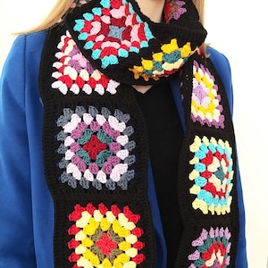 May include: A black crochet scarf with colorful granny squares. The scarf is made with a variety of colors, including red, yellow, blue, green, and purple.
