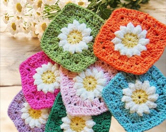 May include: A collection of crocheted granny squares with daisy motifs in various colours, including green, pink, orange, blue, and purple.