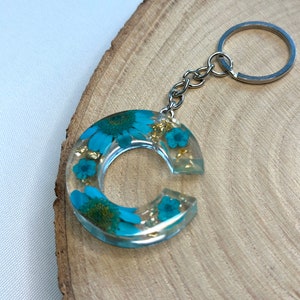 Llavero hecho a mano en resina epoxi en forma de letra | Accesorio y regalo de alta calidad con flores secas azules.