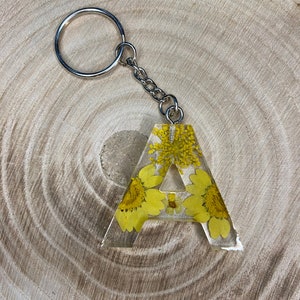 Llavero hecho a mano en resina epoxi en forma de letra | Accesorio y regalo de alta calidad con flores secas amarillas.