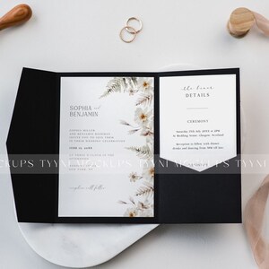 May include: A black wedding invitation suite with floral accents and gold rings. The invitation features the names "Sophia and Benjamin" and event details. A wax seal and ribbon are also present.