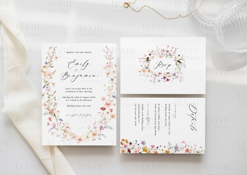 May include: Wedding invitation suite featuring a floral design. The invitation card has a wreath of watercolour flowers in shades of pink, purple and peach. The text reads "Emily & Benjamin" and includes the wedding date and time. The RSVP card features a similar floral design with the word "RSVP". The details card features a floral design and the word "Details".