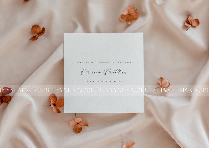Pu&ograve; includere: Un biglietto bianco con il testo "Save the Date" e "Olivia + Matthew" in calligrafia nera. Il biglietto &egrave; su uno sfondo di tessuto beige con fiori secchi.