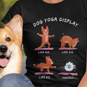 May include: A black t-shirt with the text "DOG YOGA DISPLAY" and illustrations of a dog doing yoga poses. The text "LIKE DIS" appears below each pose. The final pose shows the dog chasing a squirrel with the text "SQUIRREL..." below.