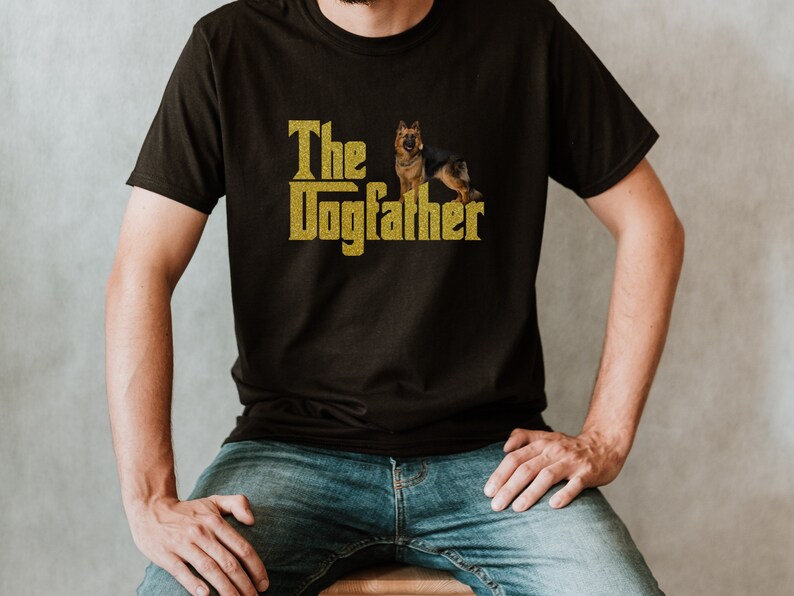 May include: A black t-shirt with a gold glitter design that says "The Dogfather" with a German Shepherd dog standing on its hind legs.