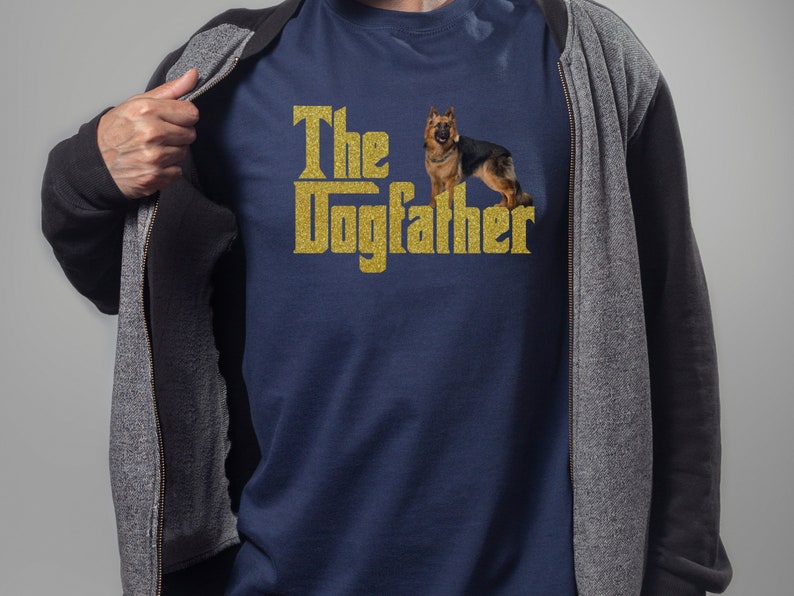 May include: A navy blue t-shirt with a gold glitter design that says "The Dogfather" with a German Shepherd dog standing next to the text.