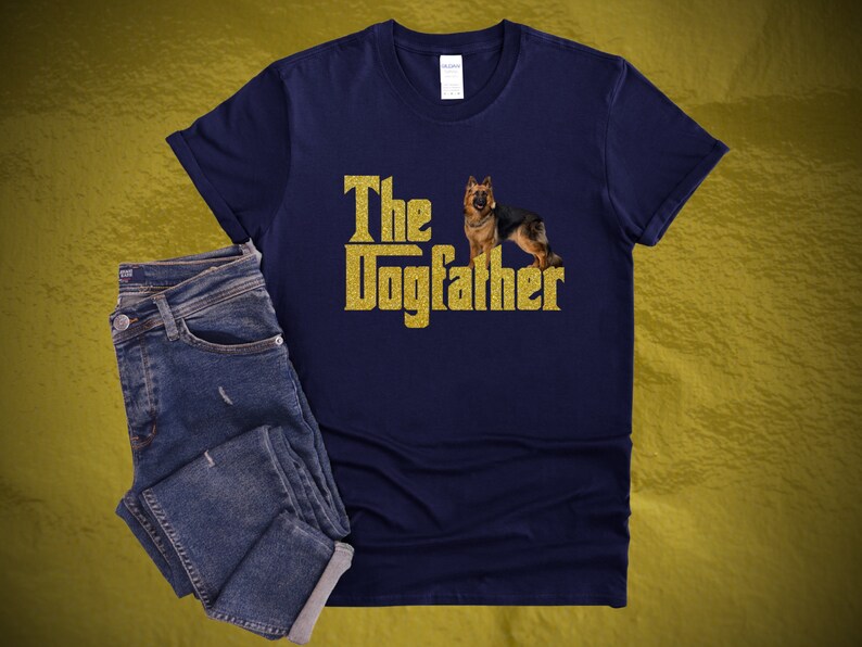 May include: A navy blue t-shirt with a gold glitter design that says "The Dogfather" with a German Shepherd dog standing in front of the text.