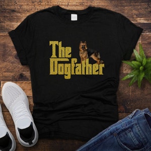 May include: Black t-shirt with gold glitter text that reads "The Dogfather" and a German Shepherd dog image.