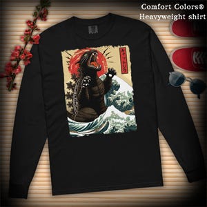 May include: Black long-sleeved shirt featuring a graphic print of a black cat monster in a Japanese wave design. The text "キサツドラ" is printed on the shirt.