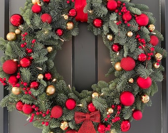 Large real Christmas wreath with red and gold baubles and red berries and lights