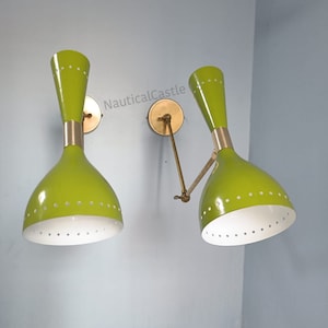Op de afbeelding: Een paar groene en witte wandlampen met messing accenten. De lampen hebben een mid-century modern design en zijn verstelbaar.