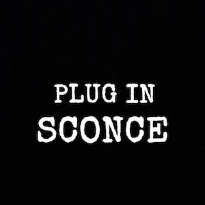 Op de afbeelding: Een zwart-wit afbeelding met de tekst "PLUG IN SCONCE" in een typemachine lettertype.