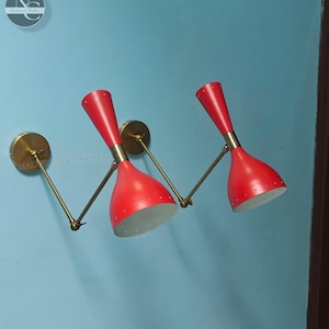 Könnte beinhalten: Zwei rote Wandleuchten aus Messing mit verstellbaren Armen. Die Leuchten haben ein modernes Design aus der Mitte des Jahrhunderts.