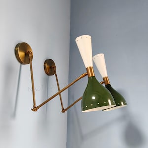 Peut inclure: Deux appliques murales de style moderne du milieu du siècle. Les lampes présentent des abat-jours vert olive avec des intérieurs blancs et des sommets coniques blancs. Les luminaires ont des bras et des plaques de montage couleur laiton.