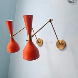 Può includere: Un paio di applique da parete rosse e in ottone con bracci regolabili. Le applique hanno un design moderno di metà secolo.