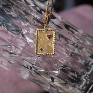 May include: Gold necklace with a rectangular pendant that says "You are your best thing" with a small heart and gemstones.