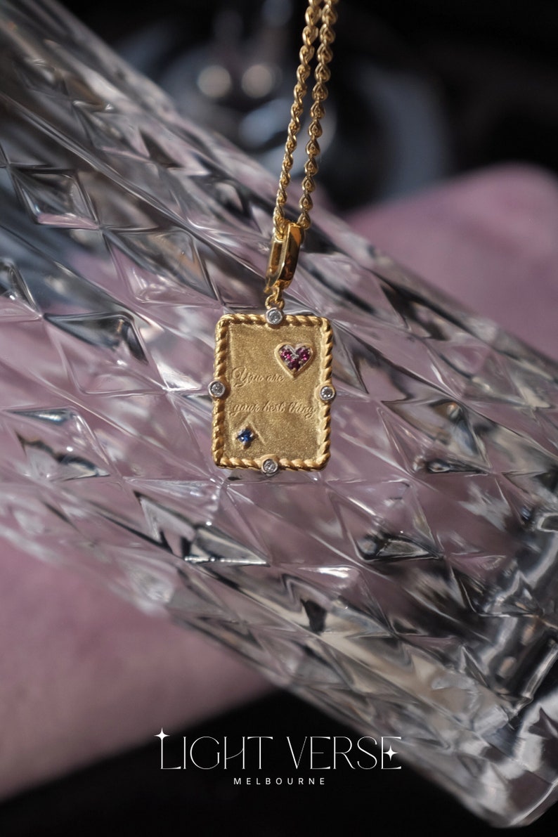 May include: Gold necklace with a rectangular pendant that says "You are your best thing" with a small heart and gemstones.