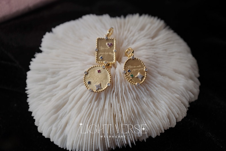 May include: Three gold pendants with colorful gemstones and engraved messages. The pendants are on a white coral background. The messages are "You are worth your kind heart", "You are worth your kind heart", and "How can we walk joy in your youth".