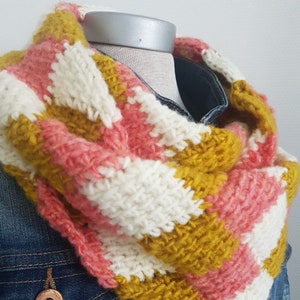 May include: A striped knit cowl neck scarf in pink, white, and mustard yellow.
