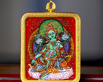 May include: A framed painting of a green deity with a golden halo, sitting on a pink lotus flower. The painting is surrounded by a gold frame with intricate details.