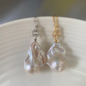Pu&ograve; includere: Due collane di perle con un ciondolo a forma di perla barocca e un ciondolo circolare tempestato di diamanti. Una collana ha una catena d'argento e l'altra una catena d'oro.
