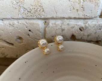 May include: A pair of gold earrings with two white pearl accents.