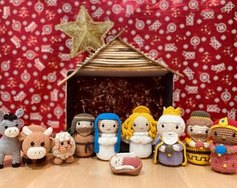 May include: A nativity scene with crocheted figures of Mary, Joseph, the three wise men, a donkey, a cow, a sheep, and baby Jesus in a manger. The figures are arranged in front of a wooden stable with a gold star on top.