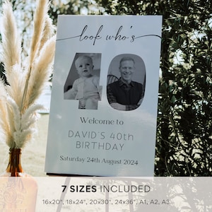 May include: A white sign with black text that says "look who's 40" with a photo of a baby and an adult man in the number 40. The text below the photo says "Welcome to David's 40th Birthday Saturday 24th August 2024". The bottom of the sign says "7 Sizes Included 16x20", 18x24", 20x30", 24x36", A1, A2, A3"