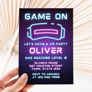 Puede incluir: Una invitación de color morado y azul neón con el texto "GAME ON" y un gráfico de auriculares de realidad virtual. La invitación es para una fiesta de realidad virtual para Oliver, que ha alcanzado el nivel 8. Incluye la dirección y la información de RSVP.