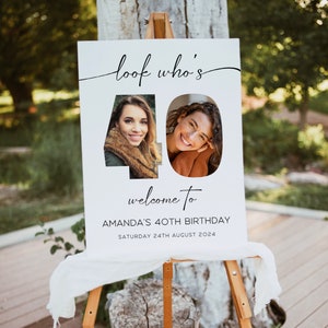 May include: A white welcome sign on a wooden easel. The sign reads "look who's 40" with two photos of a woman. Below the photos, it says "welcome to AMANDA'S 40TH BIRTHDAY SATURDAY 24TH AUGUST 2024".
