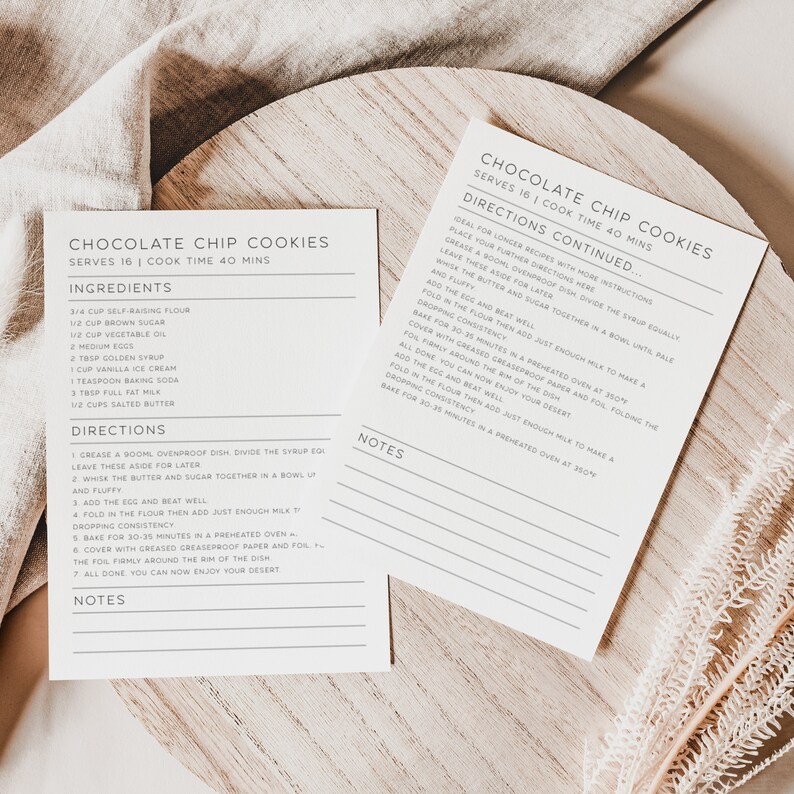 May include: Two printable recipe cards for chocolate chip cookies. The cards are white with black text and include the ingredients, directions, and notes for making the cookies. The cards are on a light brown wooden surface.