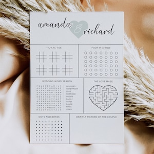 May include: A white wedding game card with the names "amanda & richard" and a heart graphic. The card includes Tic-Tac-Toe, Four in a Row, a Wedding Word Search, a Love Maze, Dots and Boxes, and a space to draw a picture of the couple.