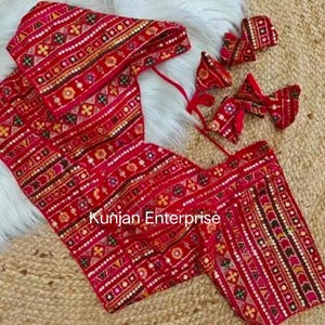 Op de afbeelding: Een rood geborduurd blouse met een geometrisch patroon en pailletten. De blouse heeft een V-hals en een strik sluiting aan de achterkant. De blouse wordt gecombineerd met drie bijpassende haarbandjes. De tekst "Kunjian Enterprise" is zichtbaar op de blouse.