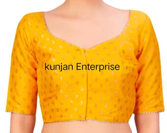 May include: A yellow blouse with short sleeves and a V-neck. The fabric features a subtle, repeating pattern, and the text "kunjan Enterprise" is printed on the front. The sleeve and neckline edges are trimmed with a decorative border.