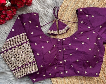 May include: A purple silk blouse with gold embroidery and a decorative tie at the back. The blouse has a scoop neck and three-quarter sleeves.