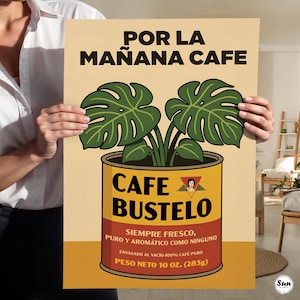 May include: A rectangular poster featuring a graphic illustration of a green monstera plant growing out of a yellow and red Cafe Bustelo coffee can. The text reads POR LA MA&Ntilde;ANA CAFE, CAFE BUSTELO, SIEMPRE FRESCO, PURO Y AROM&Aacute;TICO COMO NINGUNO, and PESO NETO 10 OZ. (283g).