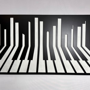 May include: Black and white metal wall art depicting a stylized piano keyboard with the keys extending into tall, thin rectangles. The artwork has a 3D effect, creating an illusion of depth.